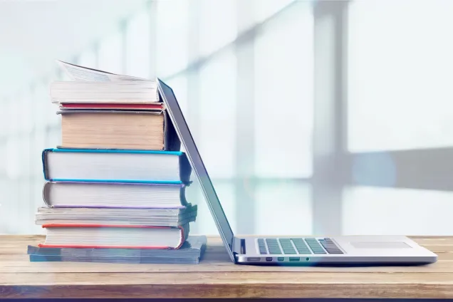 stack of books next to open laptop computer. photo